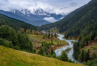 The beautiful landscape with green trees, blue snow-tipped mountains and the river is seen during a trip from Pahalgam to the Aru Valley. This region is called ‘Heaven on Earth’ and is popular with visitors traveling through Jammu and Kashmir - Photo By Supermop