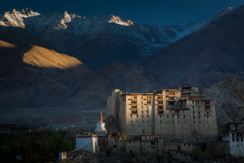 The last rays of the setting sun illuminate the former nine-story Royal Palace overlooking the city of Leh. The dark blue Tsemo Mountains form a dramatic backdrop to this 600-year old structure - Photo By Zoltan Szabo Photography