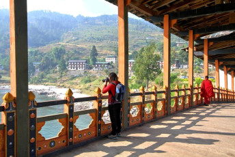 A tourist takes a picture of the Punakha Dzong in Bhutan from the Puna Mocchu Bazam. When the monastery was constructed in the 17th century, a wooden bridge was built across the Mo Chhu River. A flash flood swept it away in 1957 and it was replaced by a beautiful cantilever bridge in the traditional style
