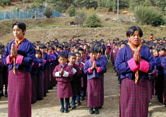 Young school children and their teachers gather for morning prayers in Bhutan. They are all wearing the traditional clothes of Bhutan © Beat Germann