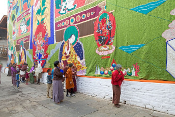 Bhutanese devotees dressed in traditional clothes pay tribute at the huge Avalokitesvara displayed at the utse or main tower at the Punakha Dzong during a birthday celebration of the 4th king. During the festival an image of the compassion of all Buddhas, the Avalokitesvara, kept inside the utse, is brought out on display. The dzong, built by Ngawang Namgyal in the middle 1600’s is one of Bhutan’s largest and most majestic monasteries © Antonella865