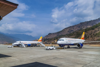 Two Drukair Royal Bhutan Airline Airbus A319 planes on the runway at Paro International Airport, one of the most challenging airports in the world because of surrounding peaks as high as 18,000 ft./5,500m. Just a few pilots are certified to land here © Kateryna Mashkevych