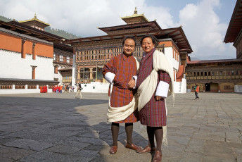 Bhutan’s national dress for men, the gho, goes back to the 17th century and consists of a knee-length robe tied at the waist with a hand woven belt, called a kera. For special occasions they add a white silk scarf called a kabney. In the picture two men pose for the camera at the Trashi Chho Dzong in Thimphu, Bhutan © Antonella865