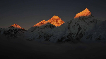 Spectacular scene of the Everest, Khumbutse and Nuptse Mountain Peaks captured in the setting sun. The peaks seem to raise out from the bank of clouds covering the lower part of the mountains © perreten