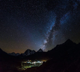 The Milky Way with millions of stars illuminate the sky above the little Sherpa village of Lobuche at the foot of the remote snow covered Himalayan Mountains in the Everest National Park in Nepal © fotoVoyager