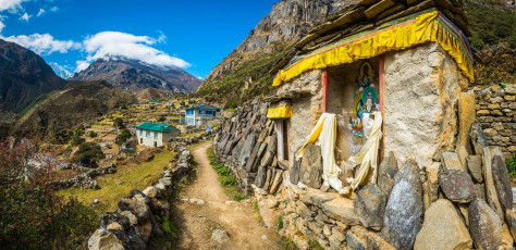 A Buddhist shrine with Mani stones inscribed with mantras on a trail leading through a little Sherpa village in the Thame Valley, Nepal. These stones are a form of prayer in Tibetan Buddhism and are usually placed beside rivers and roadsides © fotoVoyager