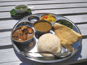 A traditional dish from Nepal enjoyed at an al fresco restaurant. Dal bhat consists of lentil soup, steamed rice and poppadum, curry chicken and pickled vegetables. This is also Nepal’s unofficial national dish © Andrey Rykov