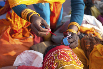 After taking a bath in the Holy water of Ganges, a female sadhu paints the bindi on a woman's forehead as a part of the blessing in Rishikesh, India © Wkok