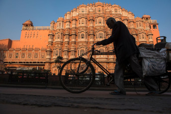 A tricycle rickshaw transporting goods is silhouetted against the beautiful red and pink sandstone Hawa Mahal, the Palace of Winds in Rajasthan. The five story exterior resembles a honeycomb with its 953 small windows called jharokhas © arun sambhu mishra