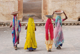 Women dressed in colorful saris gracefully carry earthenware containers on their heads at the Amber Fort in Jaipur, Rajasthan © RuiMSantos