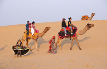 Traditional dancers in typical Rajasthani dress perform for foreign tourists who explore the Thar Desert on camelback