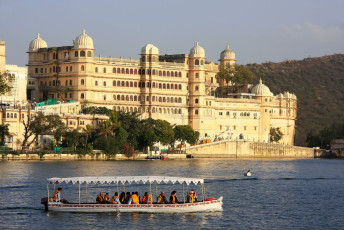 Visitors to Udaipur admire the City Palace from a boat on Lake Pichola. The palace complex was constructed over a period of 400 years by successive Mewar rulers and is the largest in Rajasthan
