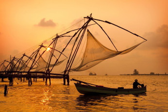 The sky turns golden as the sunsets, casting the shadow of Cochin’s Chinese fishing nets and boats in Kerala.