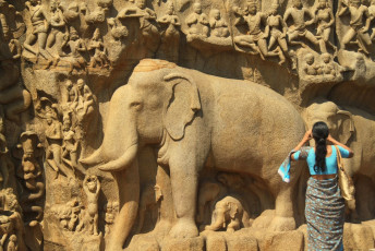 A lady clicks a picture of an elephant relief carving dating back to the 9th century on the rock wall of Arjuna’s Penance.