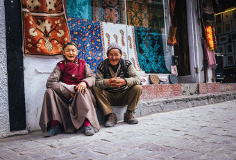 An elderly Ladakhi couple resting on the sidewalk in front of their carpet store in Leh © Soloviova Liudmyla
