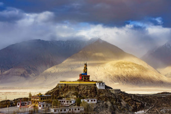The colossal statue of Maitreya Buddha sits edged against the arid Himalayan Mountains at Diskit Gompa in the Nubra Valley, Ladakh © NavinTar