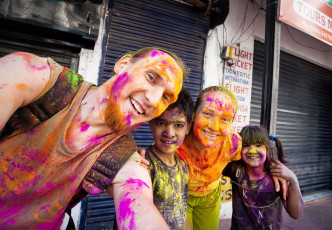 Holi is a colorful celebration enjoyed by everyone including this European couple and these Indian children with powder on their faces and clothes. © Pikoso.kz / Shutterstock