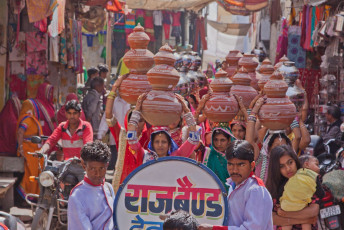 Experience the pageantry of a traditional Hindu wedding ceremony. Women carrying symbolic bowls parade through Deogarh, a Rajasthani town, while a band plays cheerful music in front. © pjhpix