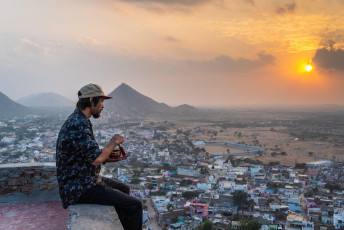 With a beautiful sunset view of Pushkar City below, this man creates intriguing sounds with his Tibetan singing bowl. © Bruno Mogli Gilioli /  Holi Color Festival Tour India