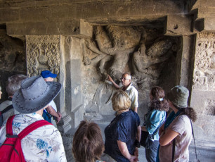 A tour guide explains the history and significance of the carved images in one of the Ellora cave temples situated near Aurangabad. The oldest temples in the group date back to 500 BCE