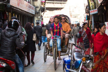 A rickshaw driver takes the foreign travelers through the crowded narrow streets of Kathmandu, Nepal © De Visu