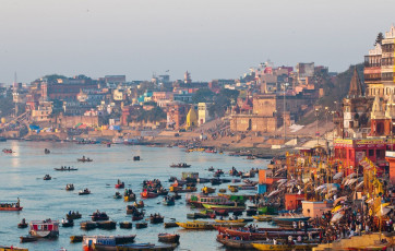 A mesmerizing morning view of the River Ganges with steps leading down to the water where boats are crowded at the Varanasi Ghats in Varanasi, India