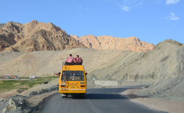 A school bus with passengers on top as well passes through the mighty Himalayas at high altitude on the Ladakh-Leh road, India © Phuong D Nguyen
