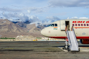 A picturesque glimpse of Air India aircraft surrounded by clouds and mountains at Kushok Bakula Rimpochee Airport which is the 23rd highest commercial airport in the world situated in Ladakh © Tooykrub