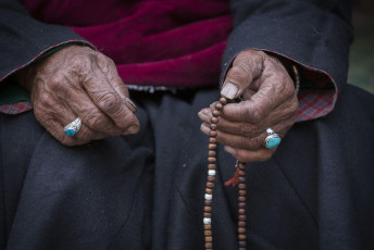 An old Tibetan woman recites the Buddhist rosary made of beads at Hemis Monastery, a very richly endowed monastery of Ladakh, North India © OlegD