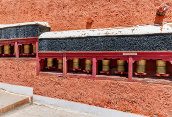Rows of prayer wheels fixed on the walls of the Thiksey Gompa Monastery in Leh Ladakh, India © Vadim Petrakov