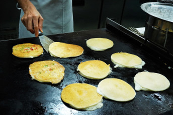 Making of delicious Oothappam dosa, a South Indian pancake, on a large flat cast iron tawa © Ajay TVM