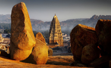 A majestic view of an ancient complex of Hampi, glowing under the bright sun, surrounded with rocks in the state of Karnataka, India © Djuly