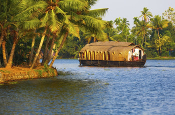 A mesmerizing sight of the houseboat which floats through the backwaters of Kerala, surrounded by the coconut trees all around, India © Roberto A Sanchez