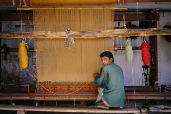 A man works on a beautiful carpet in his small shop on the streets of Jaipur, Rajasthan, India. © Costas Anton