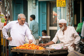 An old man purchases tomatoes from a Muslim vegetable seller on the crowded streets of Old Delhi, India. © Elena Ermakova