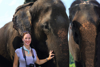 A foreign woman standing with Indian elephants waiting for her safari on the elephant along the Rapti River in the buffer zone of Chitwan National Park, Terai region, Nepal © White Forest