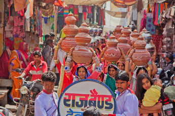 A band leads women with symbolic jugs on their heads as part of a traditional Hindu wedding ceremony in a procession through the streets of the city in rajasthan - photo by pjhpix
