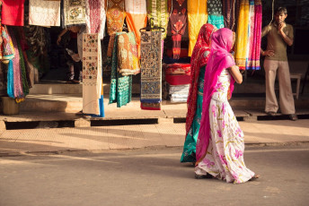 Women walk past the stores selling traditional sarees and textiles in the streets of Udaipur. @ Pablo Rogat
