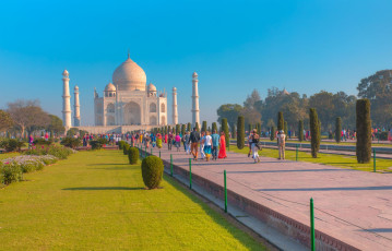 Visitors walking through the beautiful gardens to the world famous Taj Mahal in Agra. This ivory-white marble mausoleum was declared a UNESCO World Heritage Site in 1983 - Photo By  muratart