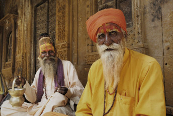 Sadhus with painted foreheads, holding their utensils sit at the Ghat along the Ganges, India. © Marianoblanco