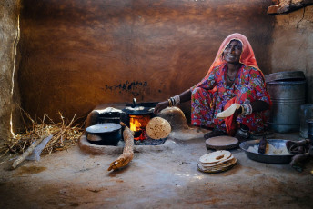 A scene from rural India wherein a woman is preparing the food (chapatis) in a mud hut in Rajasthan, India. © Costas Anton Dumitrescu