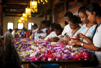 Worshippers at a table filled with flowers in the Temple of the Sacred Tooth Relic in Kandy, Sri Lanka © PhotoAliona