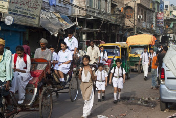 Children hanging bags on their shoulders go to school in Old Delhi. © Matyas Rehak