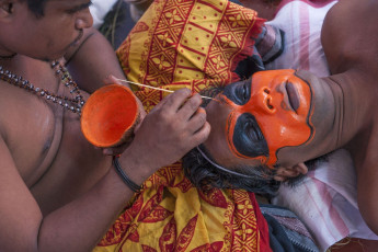 The actor gets his face painted while preparing to perform at the Theyyam festival in Kochi also known as the 'Dance of Gods'. The God’s face paint is equally as ornate - wide eyes are sunken in black pits, while the rest of his face is a vivid orange. Theyyam is a popular ritual form of worship in Kerala, India. © AJP