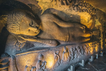 Reclining Buddha carved on the wall of the chaitya-griha or prayer hall in Cave 26 of the Ajanta Caves, a monument comprising 29 rock-cut Buddhist caves. © Paul prescott