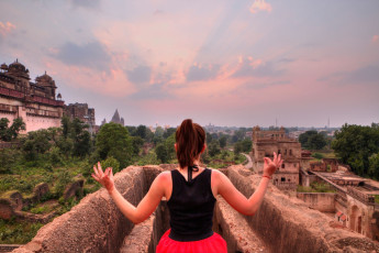 A lady meditates in a part of the extensive ruins of the 17th century Jehangir Mahal, Orchha / Tiger Safari Tour India