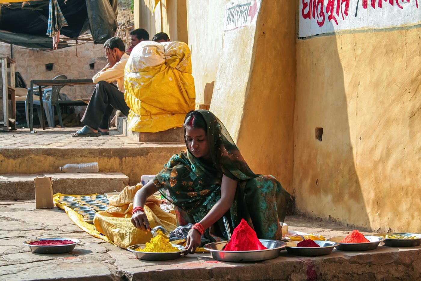 A rural woman selling herbal colours in front of the Chaturbhuj temple in Orchha, Madhya Pradesh, India. These powdered colours are organically produced and used by people across India in temples 