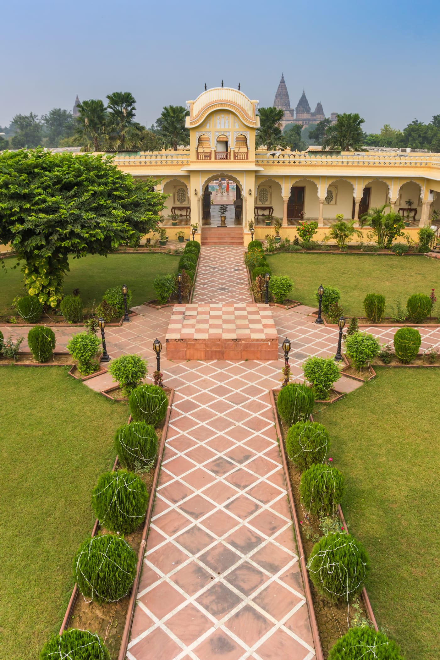 A stone pathway, lined with massive planters, in the courtyard garden of a hotel in Orchha 