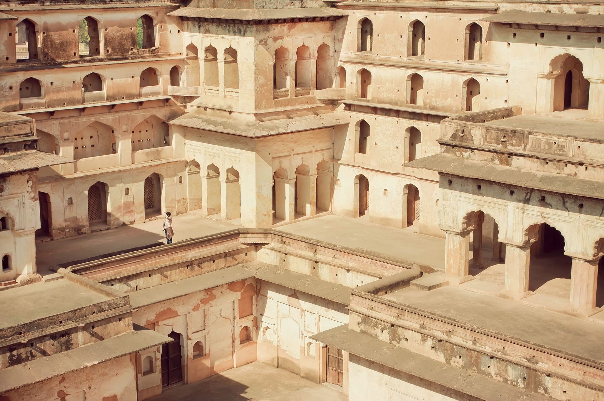 A visitor’s figure in a maze of levels in historical Raj Mahal. Several doors and windows provide an awesome view. This fort was constructed in the 17th century in Orchha, India 