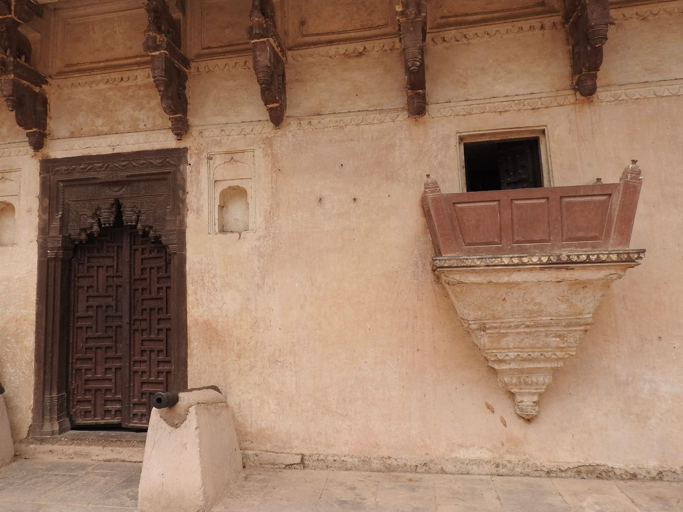 An ancient wooden door stands strong in its place as it did in the seventeenth century, much like the carved wooden supporters for the roof above, Orchha 